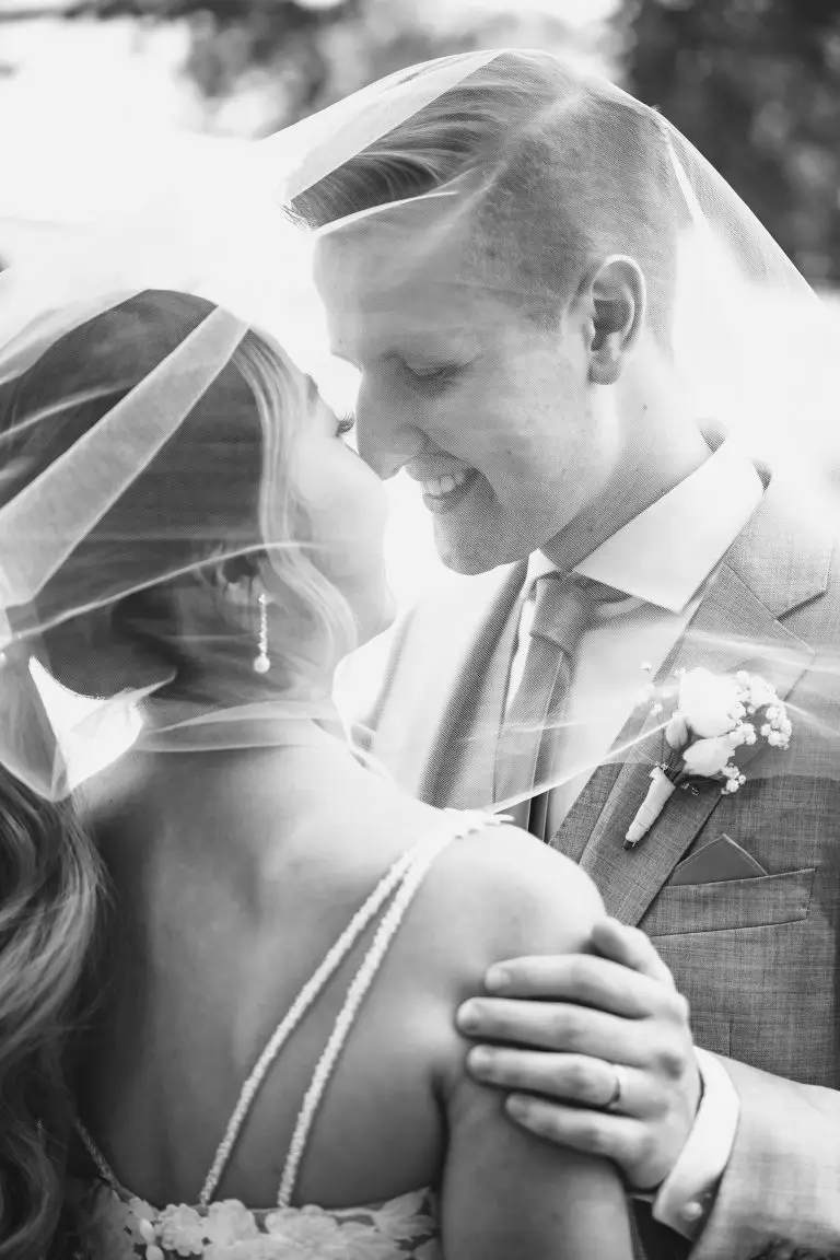 Ein Hochzeitspaar unter einem Schleier in schwarz-weiß